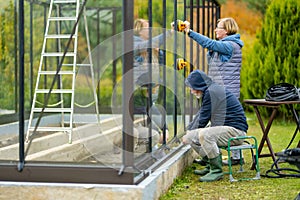 Senior couple working on a project in their garden. Man and woman constructing a greenhouse in their backyard