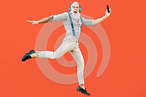 Senior crazy man jumping while listening music outdoor - Hipster male having fun dancing and celebrating life outside