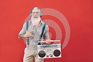 Senior crazy man listening music with headphones and vintage boombox outdoor - Hipster male having fun living in past time
