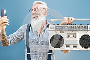 Senior crazy man using phone while listening music with vintage boombox - Hipster guy having fun using mobile smartphone