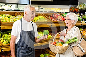 Senior customer and worker discussing vegetables