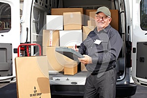 Senior delivery man with parcel near truck.