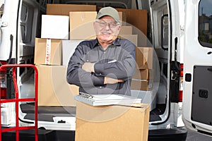 Senior delivery man with parcel near truck.