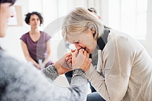 A senior depressed woman crying during group therapy.