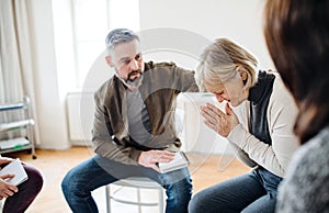 A senior depressed woman crying during group therapy.