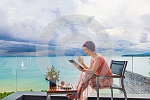 Senior digital nomad woman working at luxury villa in Phuket. andaman sea as background photo