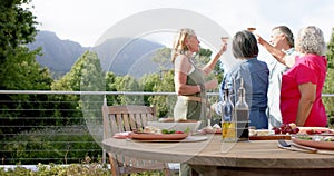 Senior diverse group enjoys a meal outdoors, with copy space