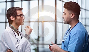 Senior doctor cheerfully talking to his colleague