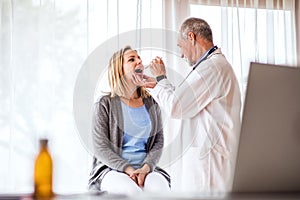 Senior doctor examining a young woman in office.