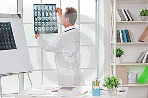 Senior doctor at his office in hospital looking rentgen