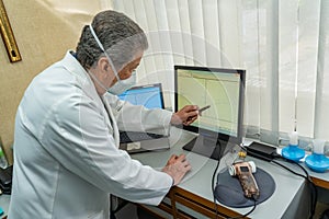 Senior doctor looking the medical results at computer