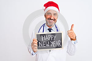 Senior doctor man wearing christmas hat holding blackboard over isolated white background happy with big smile doing ok sign,