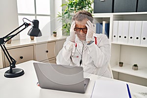 Senior doctor man working on online appointment with hand on head, headache because stress