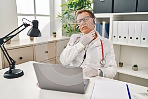 Senior doctor man working on online appointment touching painful neck, sore throat for flu, clod and infection