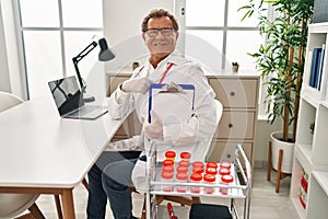 Senior doctor man working with samples pointing finger to one self smiling happy and proud