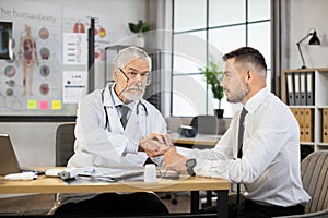 Senior doctor measuring pulse on patient wrist