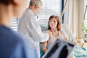 Senior doctor and nurse examining a woman patient in hospital.