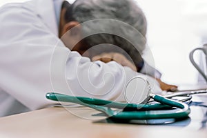 Senior doctor overwork Tired and sleeping on his deck at medical office.