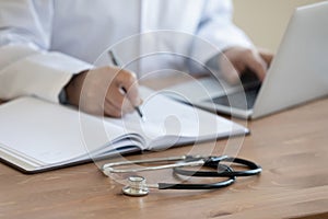 Senior doctor physician working with stethoscope on desk, closeup