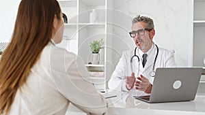 A senior doctor shares a treatment plan with a young female patient during a consultation