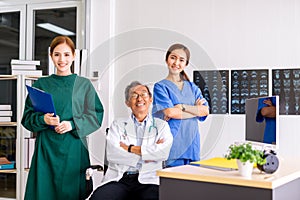 Senior Doctor sitting In Center Of Team with nurse and female doctor Surgeon portrait in office at hospital.