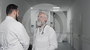 Senior doctor smiling cheerfully talking to his colleague