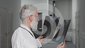 Senior doctor smiling to the camera while examining x-ray scans