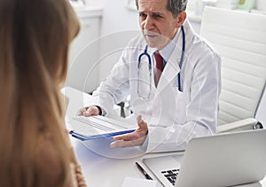 Senior doctor talking to woman in doctorâ€™s office