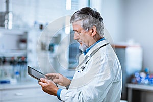 Senior doctor using his tablet computer at work