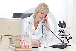 Senior doctor woman speaking phone at office