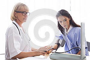 Senior doctor women is measuring patient pressure in examination room of hospital