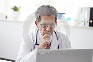 Senior doctor working with a laptop in doctorÃ¢â¬â¢s office photo