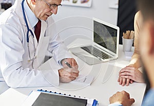 Doctor writing a prescription for his patients photo