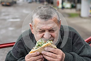 Senior driver eating lyulya kebab in lavash near his car