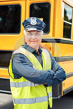 Senior driver standing near school bus crossed arms smiling confident