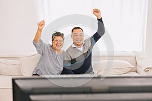 Senior eldely asian family old man and woman enjoy happy watching tv holiday activity together at home