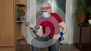 Senior elderly caucasian man making weight lifting dumbbells exercising at home during coronavirus