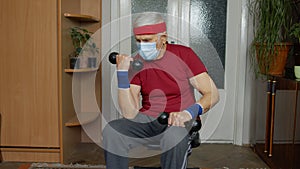 Senior elderly caucasian man making weight lifting dumbbells exercising at home during coronavirus