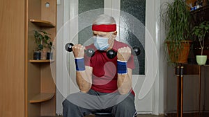 Senior elderly caucasian man making weight lifting dumbbells exercising at home during coronavirus