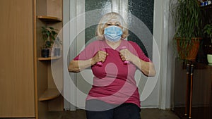 Senior elderly caucasian woman making weightlifting dumbbells exercising at home during coronavirus