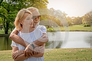 A senior elderly couple cuddle in a park in summer time