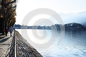 Senior elderly couple walking together outdoors along the italian mountain lake district Como. Lecco, Italy - November