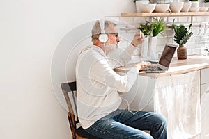 Senior elderly man making online payments using laptop. Old grandfather doing shopping ecommerce with credit card