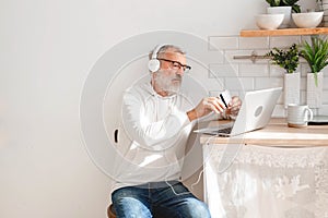 Senior elderly man making online payments using laptop. Old grandfather doing shopping ecommerce with credit card