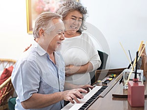 Senior elderly man plays piano in nursing home listened to by elderly woman,Retreatment elderly asian grandmother and grandfather