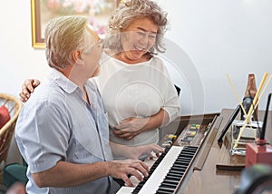 Senior elderly man plays piano in nursing home listened to by elderly woman,Retreatment elderly asian grandmother and grandfather