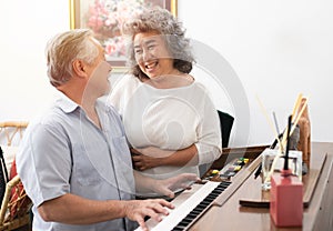 Senior elderly man plays piano in nursing home listened to by elderly woman,Retreatment elderly asian grandmother and grandfather