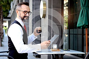 Senior elderly mature business man using digital table during having a coffee at outdoor cafe, happy people taking a break from