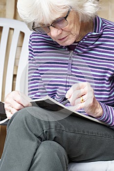 Senior elderly person keeping mind active by doing crossword puzzle