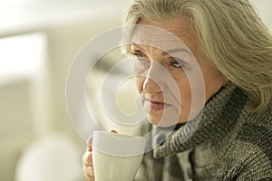 Senior elderly sick woman drinking tea at home